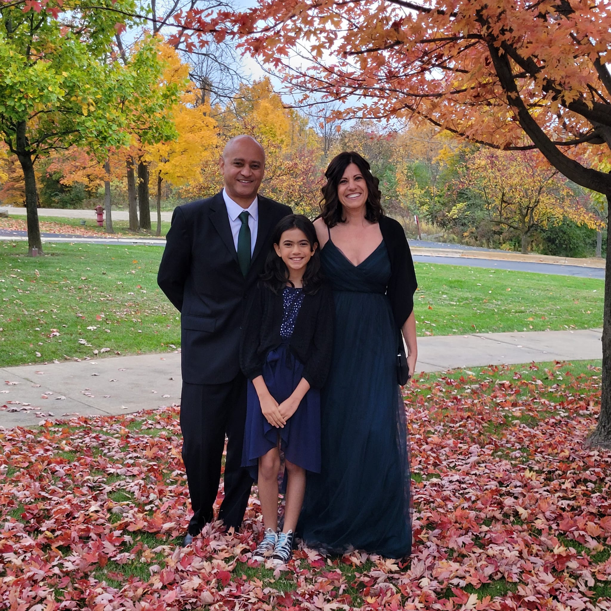 Rose, Vitor e Luisa vestidos para um casamento com as áarvores com as cores do outono de Michigan ao fundo.